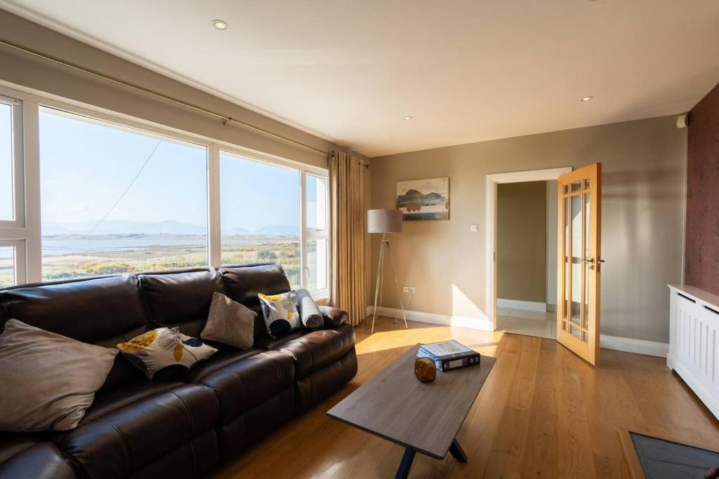 a living room with a leather couch and a table at Inch by the Sea - Sea Views in Inch