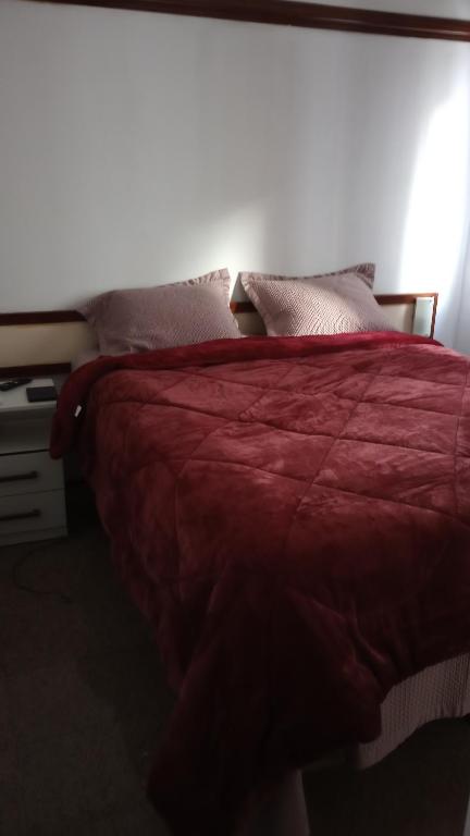 een bed met een rood dekbed en kussens bij Villa costeira Flat in Fortaleza