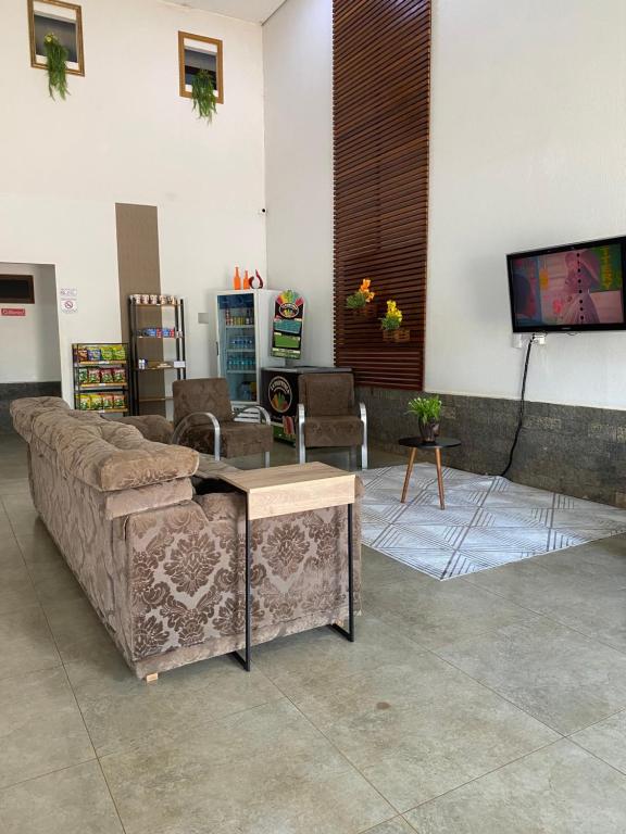 un soggiorno con divano e TV a schermo piatto di Oriente Hotel Outlet a Campo Novo do Parecis