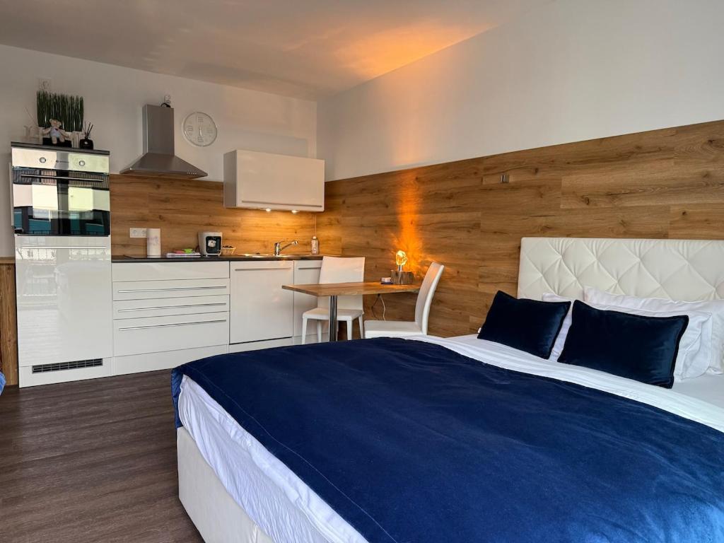 a bedroom with a large bed and a kitchen at Maritimes Luxusapartment in Rostock