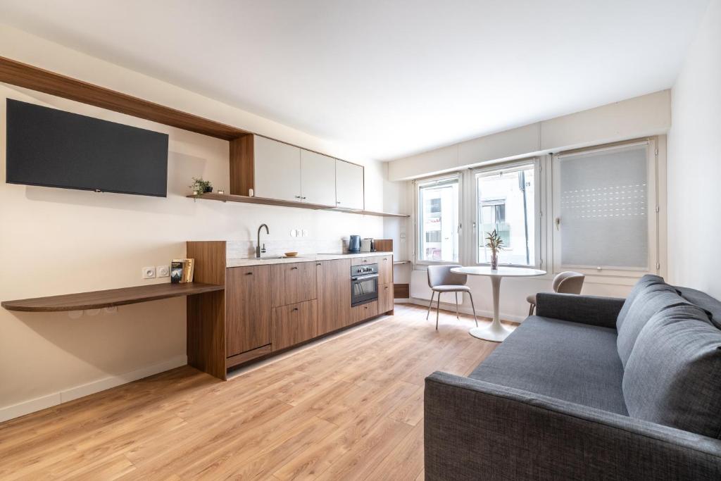 un salon avec un canapé et une cuisine dans l'établissement Studio Cozy Design - Batignolles, à Paris