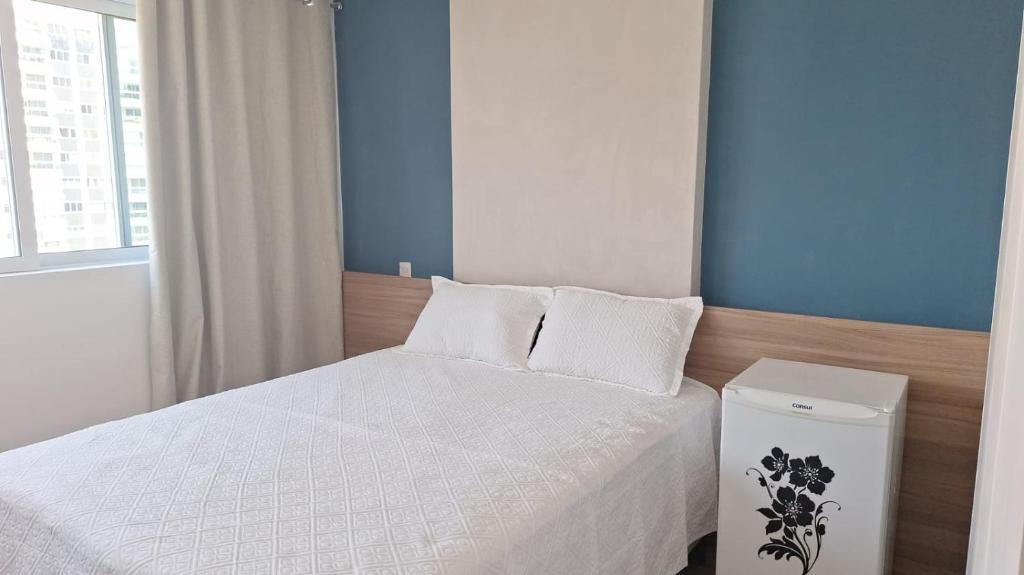 a small bedroom with a white bed and a window at Ilha Pura Barra in Rio de Janeiro