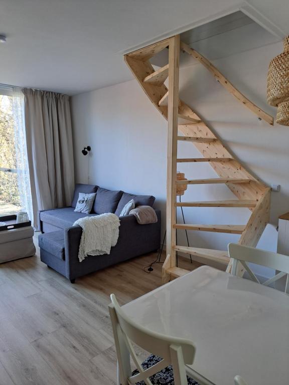 Una sala de estar con un sofá azul y escaleras. en Vakantiehuis in de polder, en Lewedorp