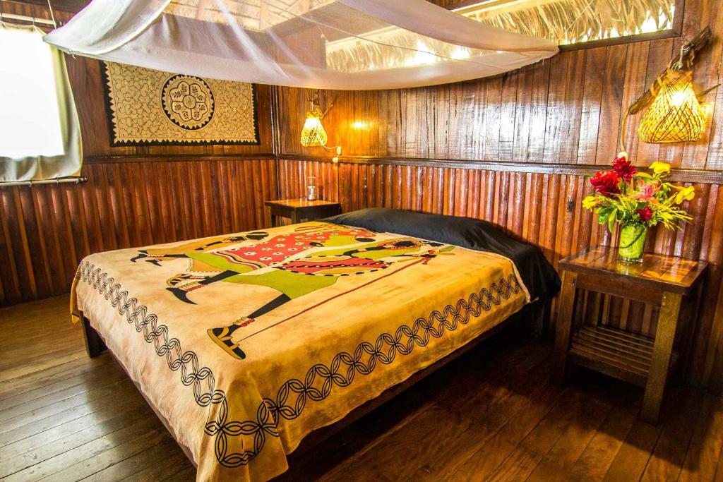 a bedroom with a bed and a table with flowers at Corto Maltes Amazonia Lodge in Puerto Maldonado