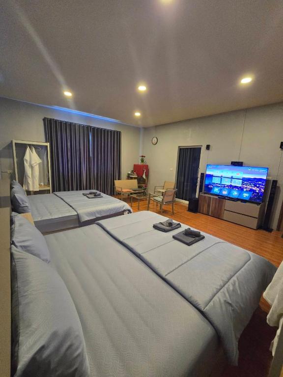 a large bedroom with two beds and a flat screen tv at Chaba 4 family in Nakhon Nayok