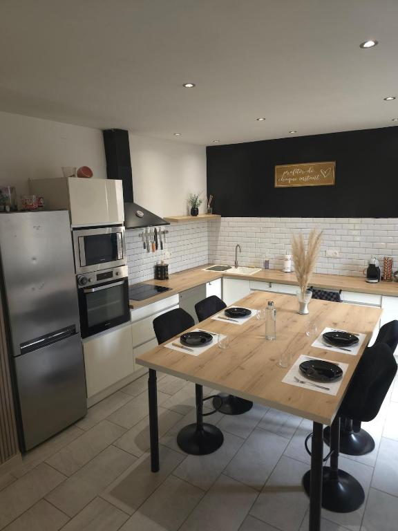 une cuisine avec une table en bois et un réfrigérateur dans l'établissement lartdeschoix, à Labégude