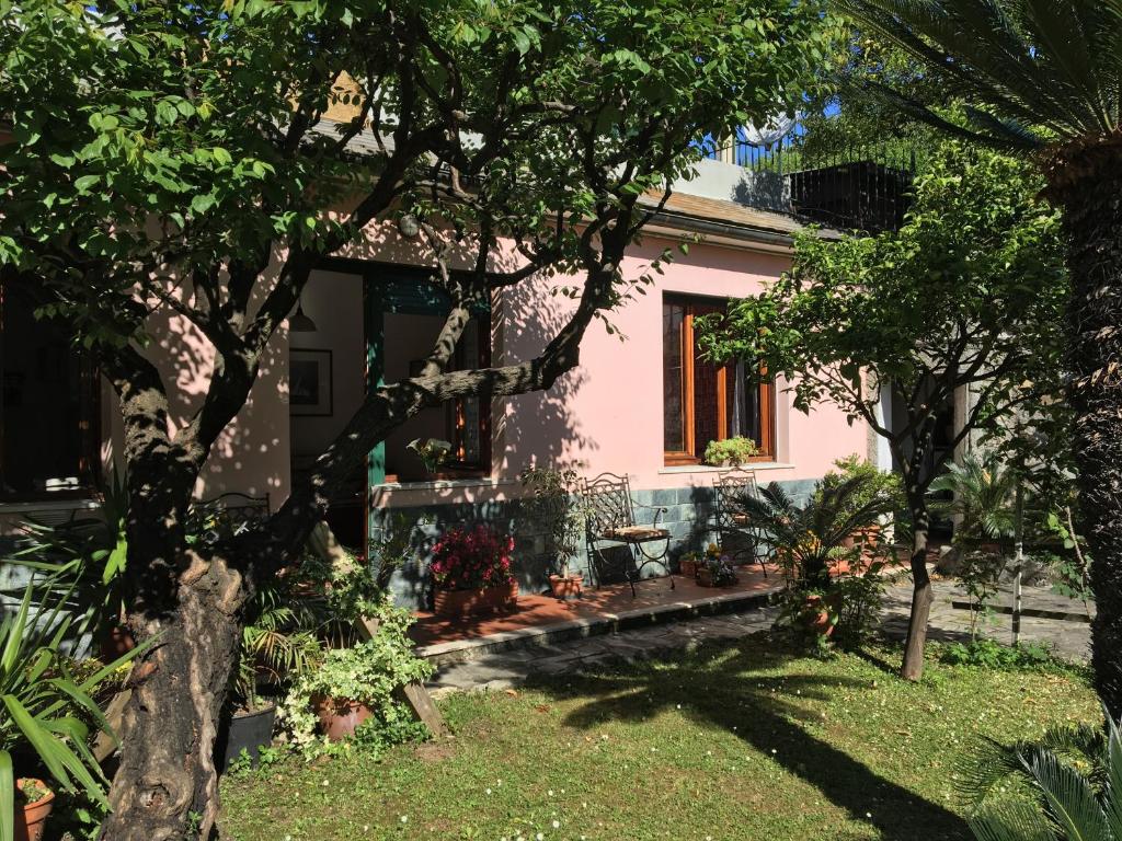 ein rosafarbenes Haus mit Bäumen im Hof in der Unterkunft Casa Tra Il Verde E Il Blu in Genua