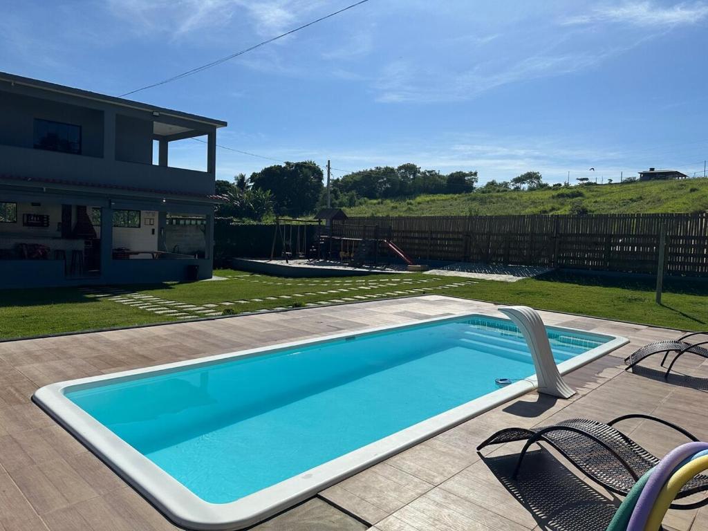 a swimming pool with two chairs and a house at Sítio Recanto da Mata - Lagoa do Siri in Marataizes