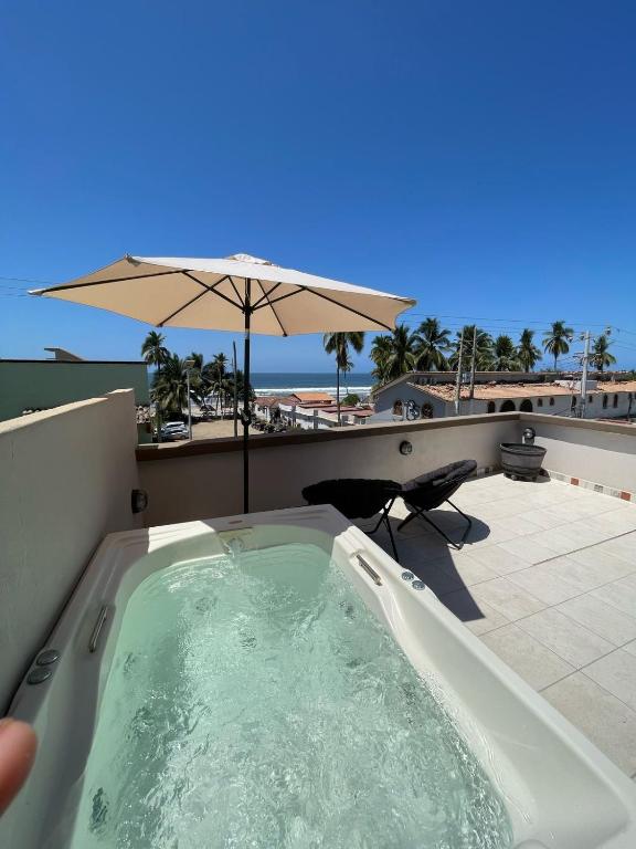 a hot tub on a balcony with an umbrella at La Altanera in Troncones
