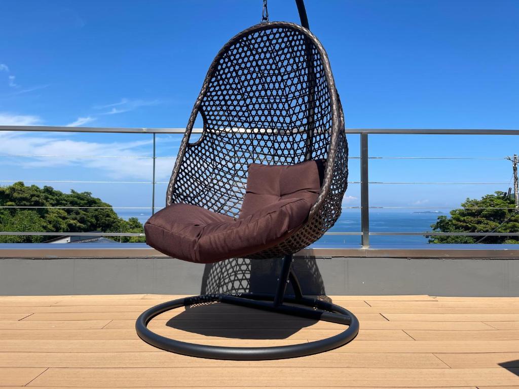 a wicker chair sitting on a balcony with a view at StellaMarina~海の星　ATAMI in Shimo-taga