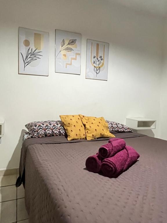Una cama con almohadas moradas y amarillas. en Depto25nuevo, en Mendoza
