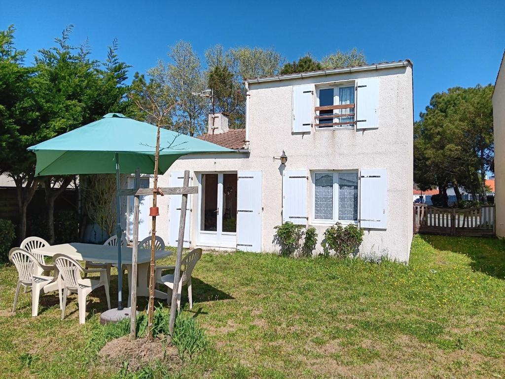 une table avec un parasol vert devant une maison dans l'établissement Maison agréable entre mer et campagne, proche plage et centre-ville, animaux permis - FR-1-476-98, à Grues