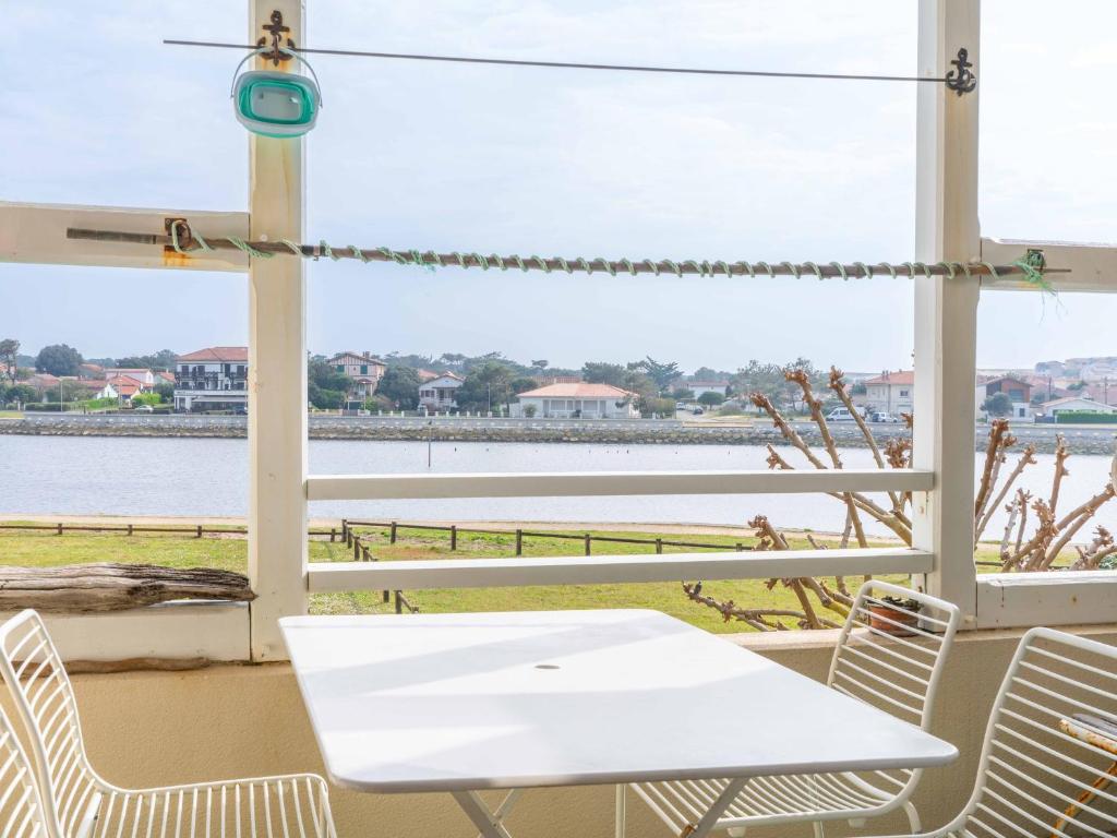 - une table et des chaises sur une terrasse couverte offrant une vue sur l'eau dans l'établissement Appartement pour 4 avec vue sur le courant à Mimizan Plage, parking inclus - FR-1-50-172, à Mimizan