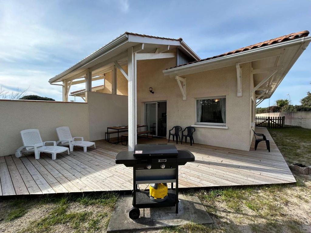 - un barbecue sur une terrasse en bois devant une maison dans l'établissement Villa lumineuse proche plage pour 8 personnes - FR-1-831-5, à Biscarrosse