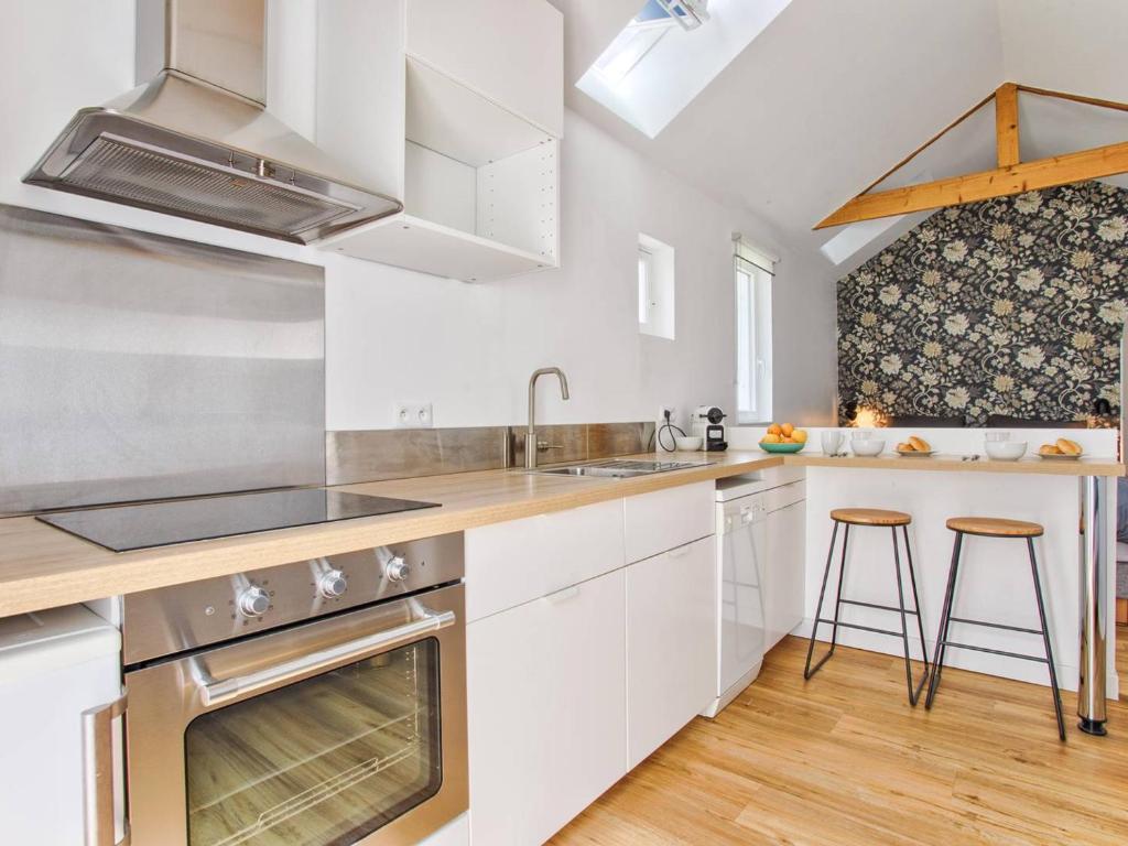 une cuisine avec des armoires blanches, un évier et une cuisinière dans l'établissement Maisonnette cosy indépendante au centre de Merville-Franceville - FR-1-788-64, à Merville-Franceville-Plage