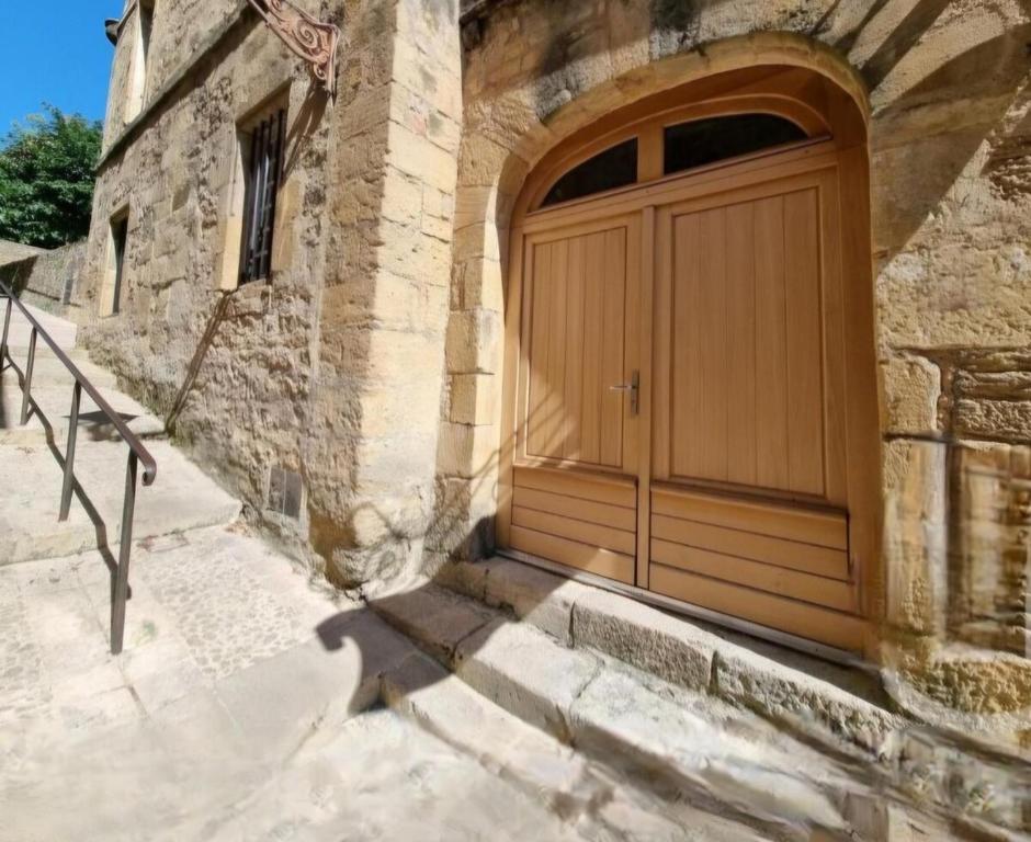 une grande porte en bois sur le côté du bâtiment dans l'établissement LA MAISON VALENTIN AU COEUR DE LA CITE MEDIEVALE, à Sarlat-la-Canéda