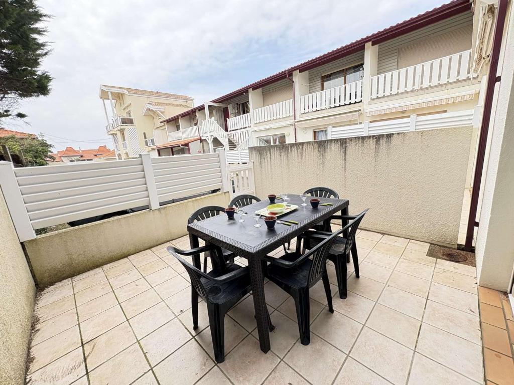 une table noire et des chaises sur une terrasse dans l'établissement La Garole 1 – Idéal pour 4 personnes près de l'Océan - FR-1-831-1, à Biscarrosse