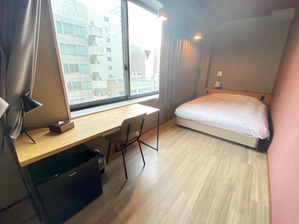 札幌市にあるWISE OWL HOSTELS SAPPOROのベッドと机と窓のある寝室