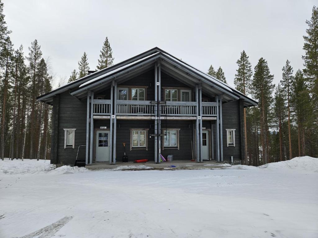 a large wooden house in the snow with trees at Levi Happi in Kittilä