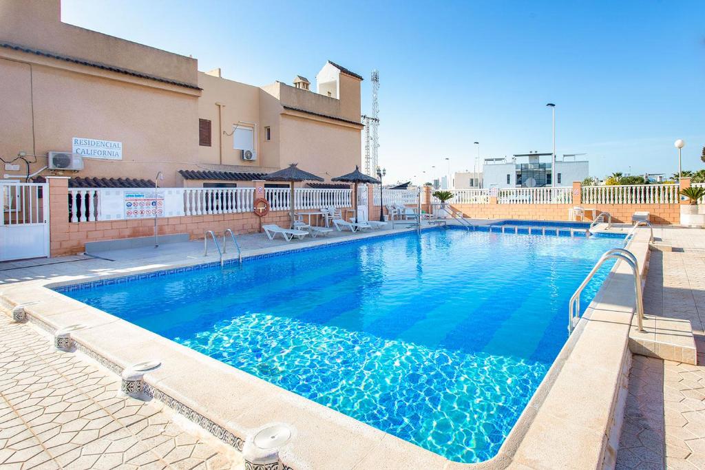 una piscina con acqua blu di fronte a un edificio di Taga 27 a Torrevieja