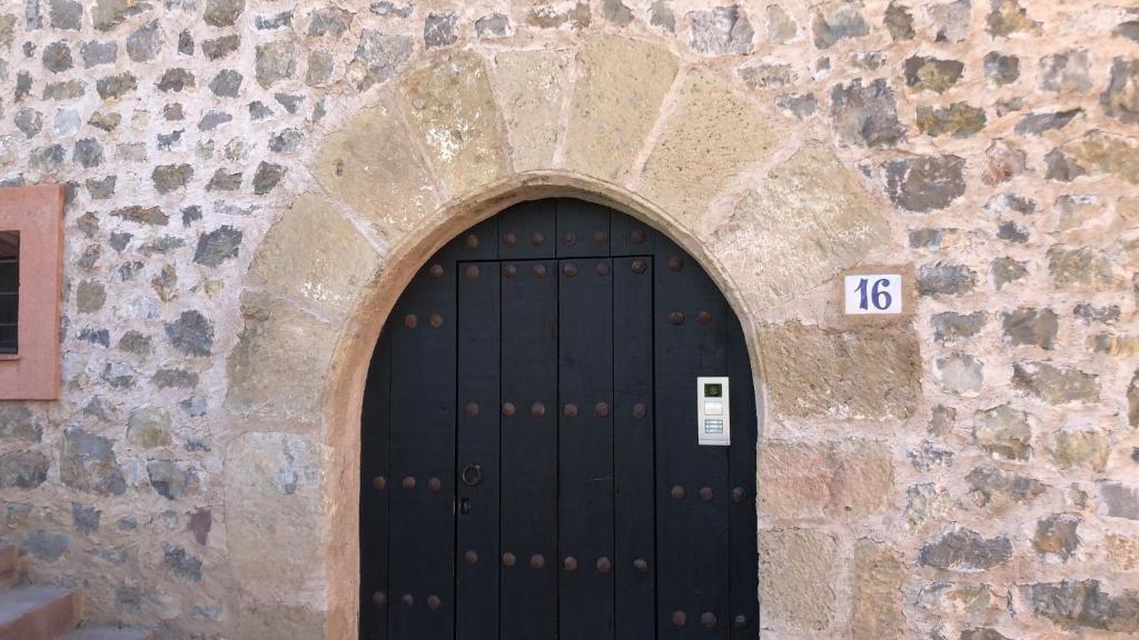 a black door in a stone wall with the number at casa bilborazin in Albarracín