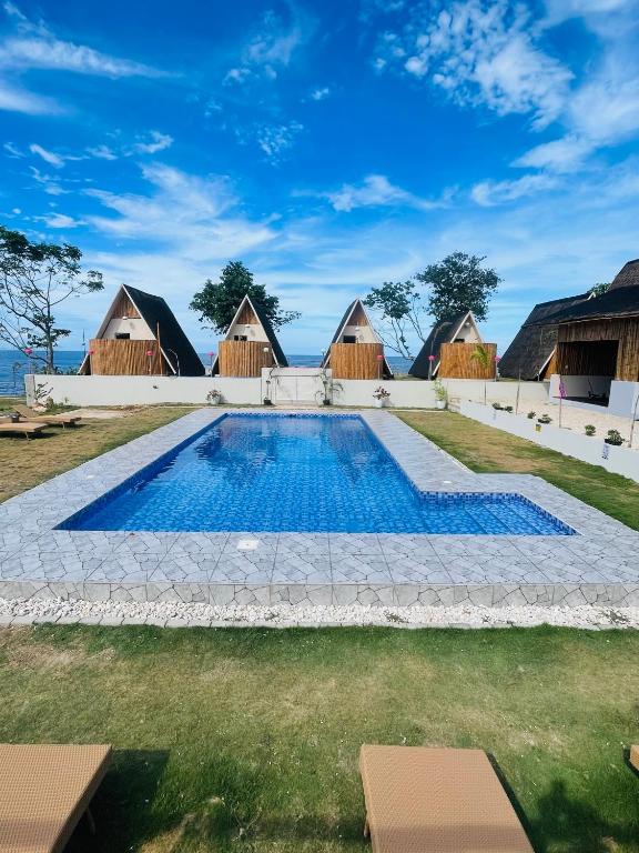 a swimming pool in front of some thatched huts at Seabreeze Haven Resort in Maria
