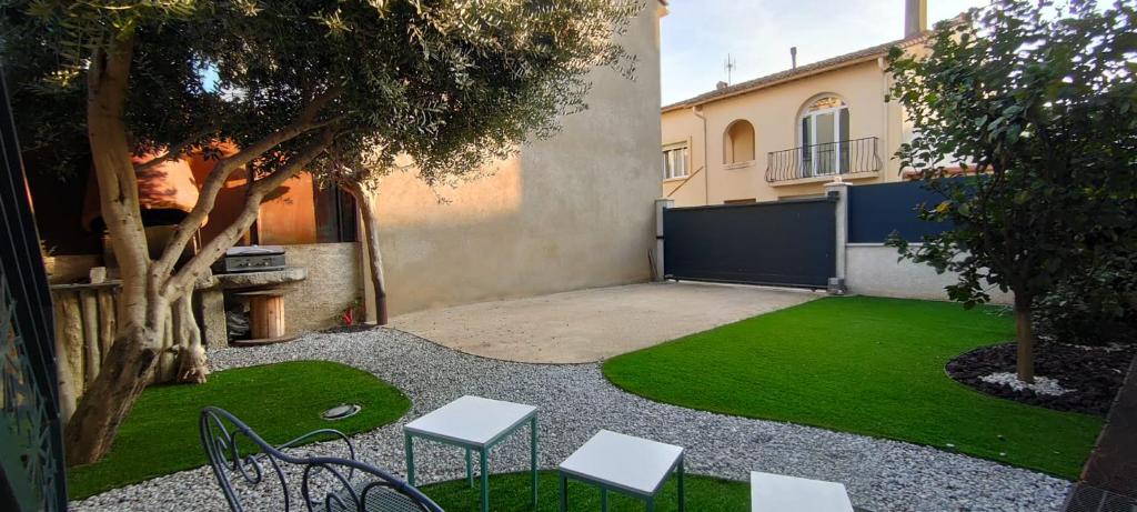 une cour avec des chaises, un arbre et un bâtiment dans l'établissement Spacieuse maison de vacances à proximité des plages, à Torreilles
