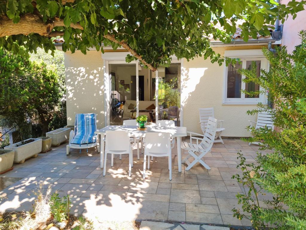d'une terrasse avec une table et des chaises blanches. dans l'établissement Villa 3 chambres au centre de Saint Mandrier village, à Saint-Mandrier-sur-Mer