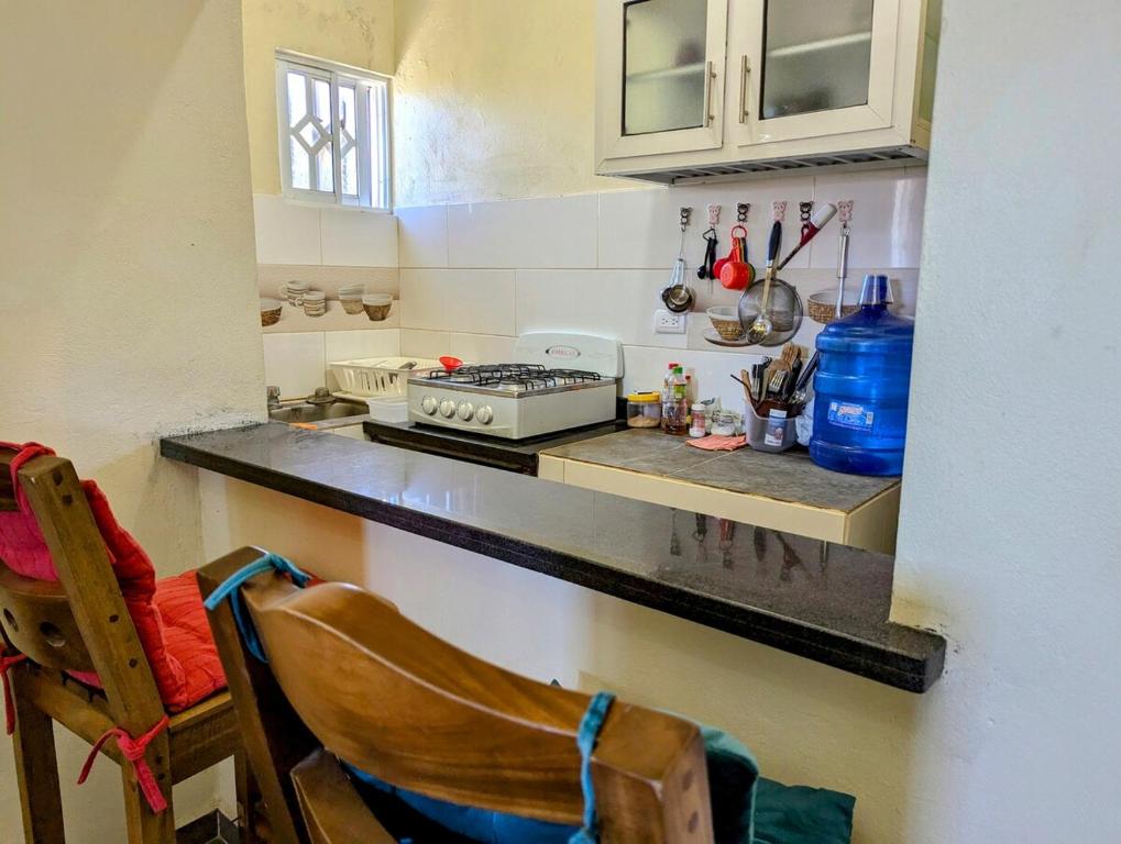 a kitchen with a stove and a counter with a chair at Buenos Aires Apartments in Río San Juan