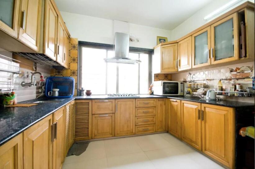 eine große Küche mit Holzschränken und einem Fenster in der Unterkunft Luxurious BnB next to Corporate hubs in Jāmb