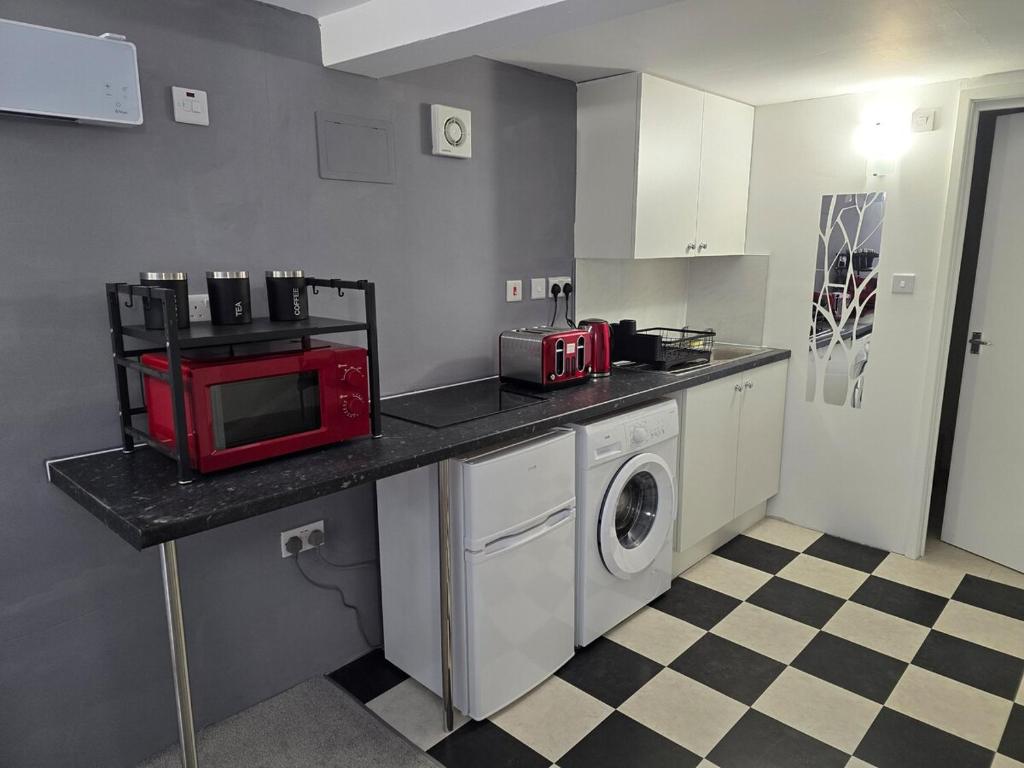 a kitchen with a microwave and a washing machine at Hidden Putney-Studio Flat in London
