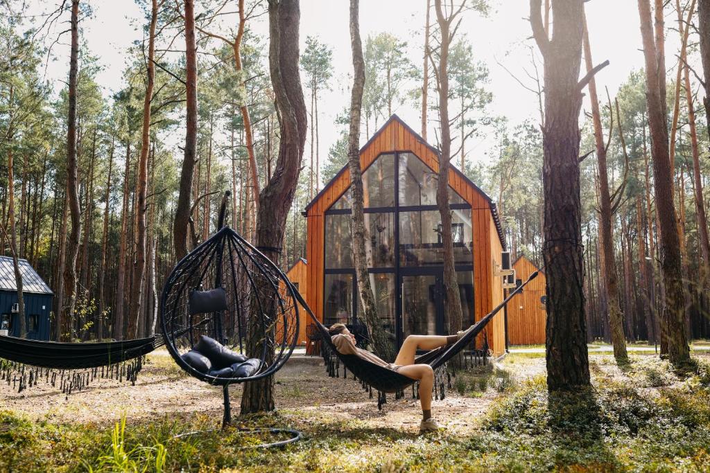 a couple of people sitting in hammocks in a forest at Wyjątkowy domek w kompleksie Patyki Las Możliwości in Zelów