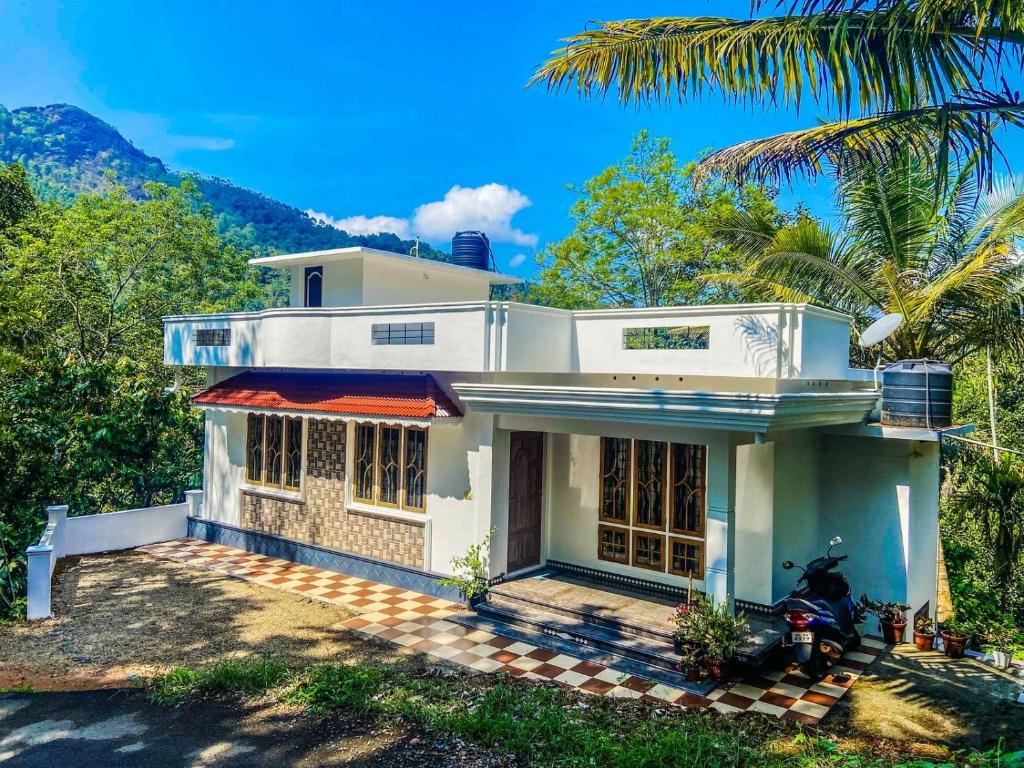 a house with a motorcycle parked in front of it at The Lovely Home Stay in Munnar