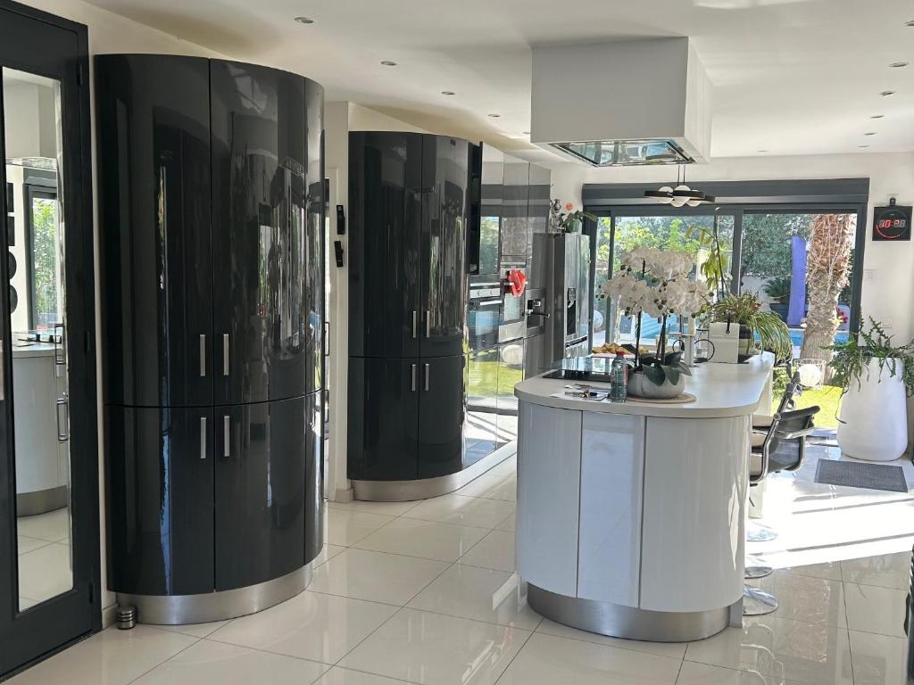une cuisine avec des armoires en noir et blanc et un comptoir dans l'établissement LOCATION Vacances VILLA PISCINE JARDIN, à La Grande Motte