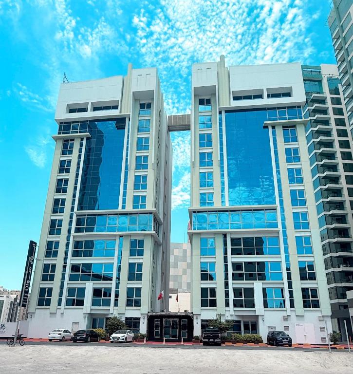 two tall buildings with cars parked in front of them at Swan Towers Juffair in Manama