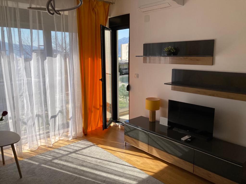 a living room with a television and a large window at Sears Residence Apartments in Tivat