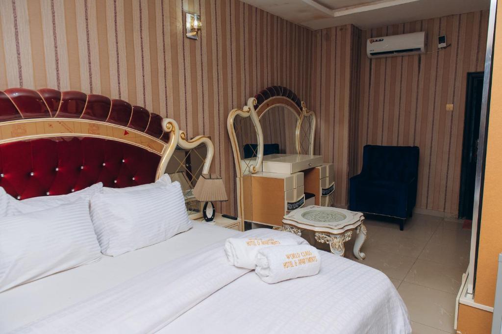 a hotel room with a bed and a chair and a desk at World Class Hotel & Apartments in Abuja