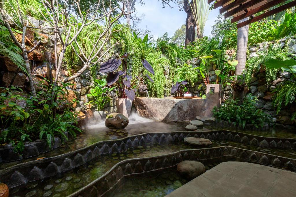a garden with a waterfall in the middle at Lynnaya Urban River Resort in Siem Reap