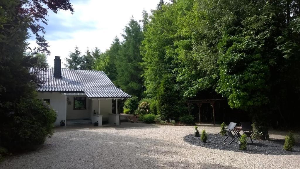 a small white house with a gravel driveway at Ferienhaus In Im Trieschelbach Mit Großem Garten in Hermeskeil