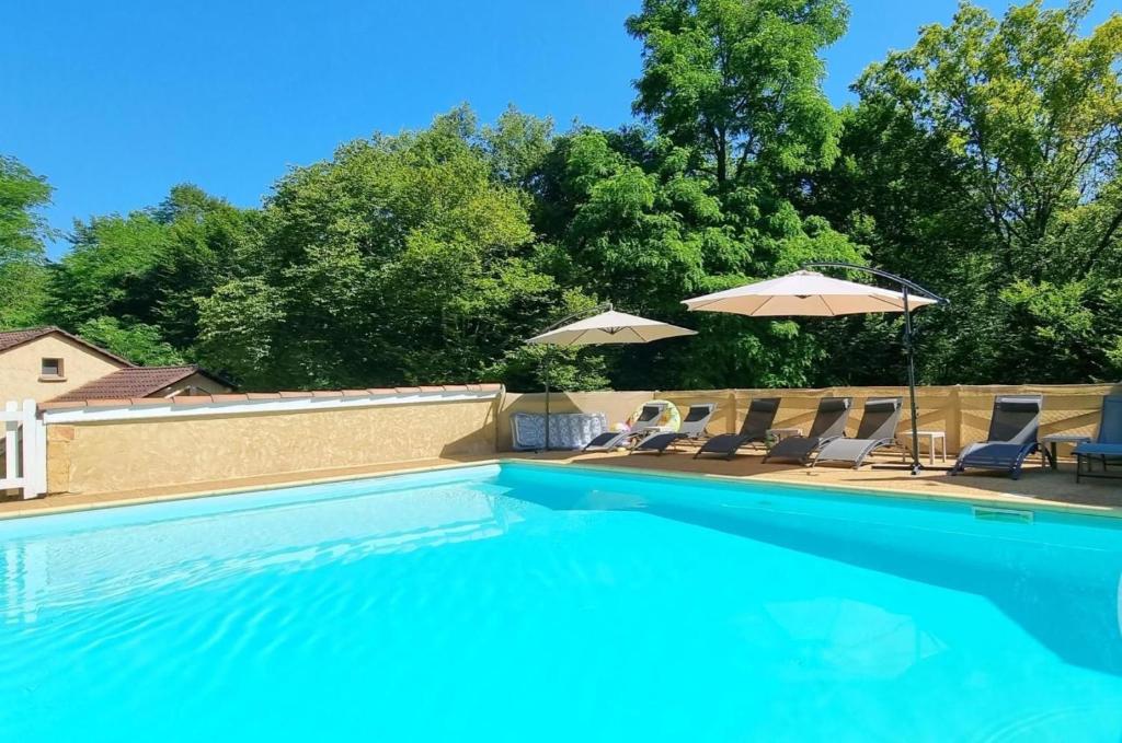 une piscine avec chaises et parasols dans l'établissement Gîtes du Bois de Bontemps, à Sarlat-la-Canéda