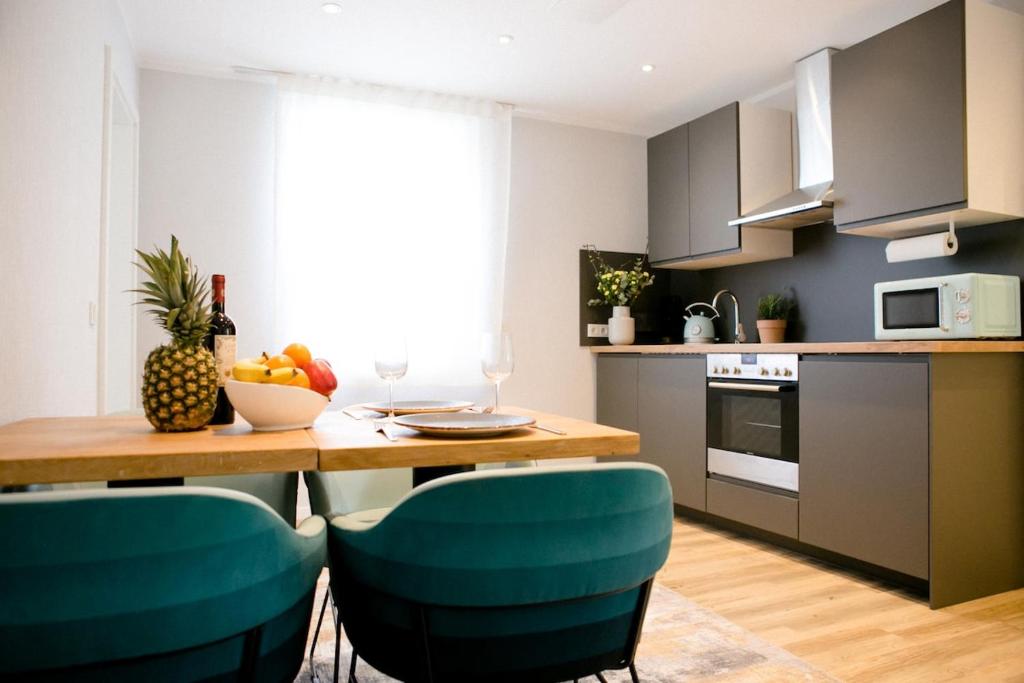 a kitchen with a wooden table and blue chairs at bonquartier - LUXAPT#5 Gemütliches, stilvolles Apartment mit Self Check-In, voll ausgestatteter Küche, Klimaanalage & Parkplatz in Sankt Augustin
