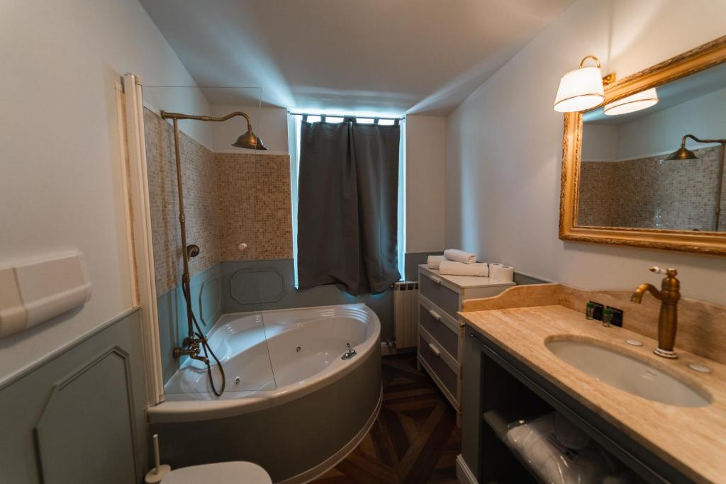 a bathroom with a tub and a toilet and a sink at Locanda Gaudemus Boutique Hotel in Sistiana