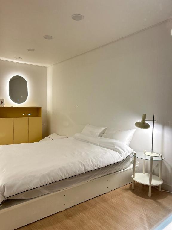 a white bedroom with a large bed and a table at Momo House in Gimhae