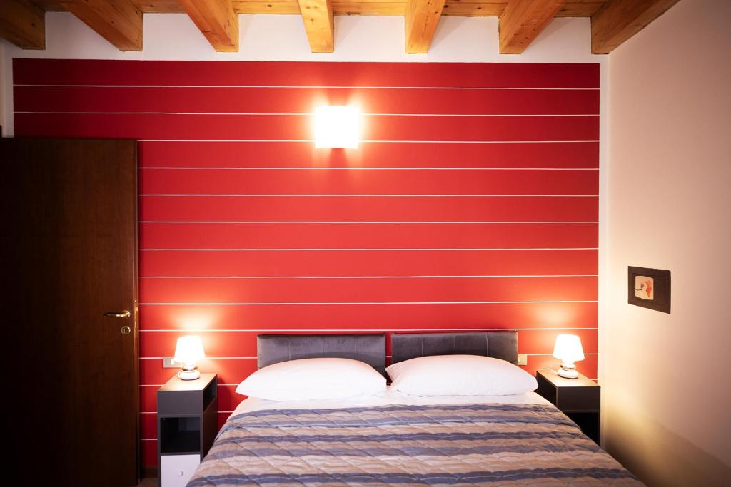 a bedroom with a red wall with a bed and two lamps at Salix Home in Lazise