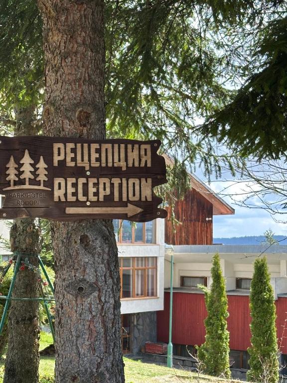 a sign on a tree in front of a building at Парк-хотел Родопи in Churen