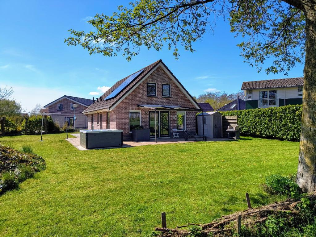 a house with a lawn in front of it at Komfortables Ferienhaus mit Garten, Weitblick und Whirlpool in Tzummarum