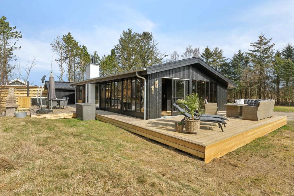 a black house with a wooden deck in a field at Cozy Summer House In North Jutland in Jerup