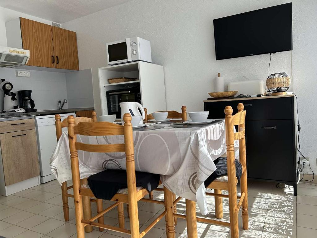une cuisine avec une table avec des chaises et un micro-ondes dans l'établissement Centre-ville, proche plage - Appt 2P cabine, 4 pers avec parking privé, Le Grau-du-Roi - FR-1-250-114, au Grau-du-Roi