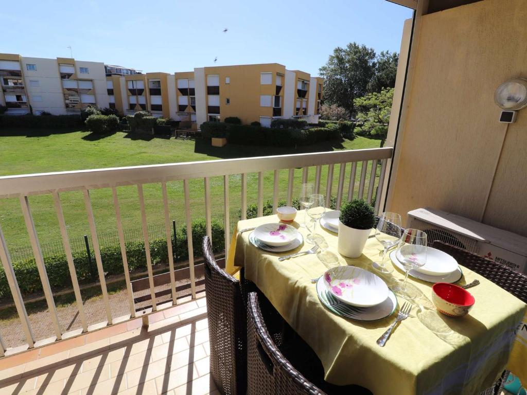 une table avec des assiettes et des verres sur un balcon dans l'établissement Studio cabine climatisé, proche plage, parfait pour 4 pers. - FR-1-307-123, au Grau-du-Roi