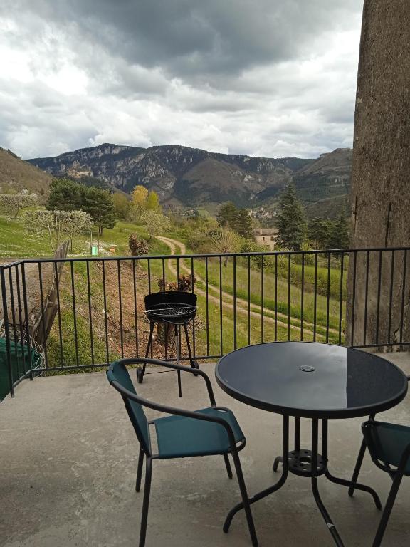 une table et des chaises sur un balcon avec vue dans l'établissement gite de la via ferrata liaucous, à Mostuéjouls